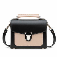 Black leather crossbody handbag with beige flap, silver buckle, and top handle