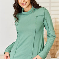 Emerald green long sleeve knit top with mock neck and exposed seam panel