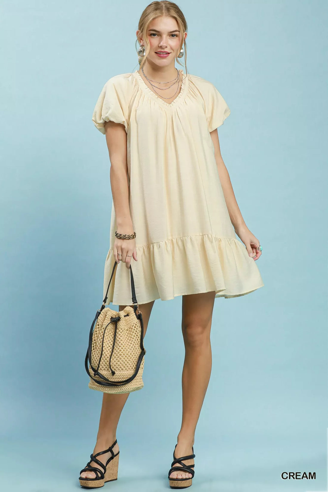 Cream mini shift dress with V-neck, puff sleeves, and ruffle hem, side view.