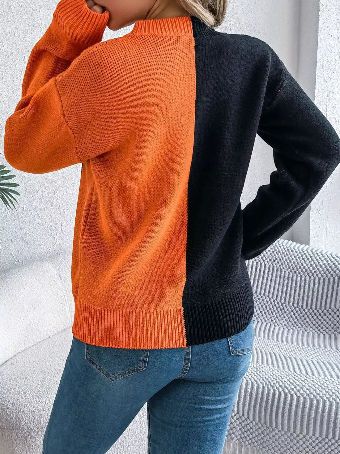 Two-tone knit sweater with pumpkin face graphic, back view in orange and black