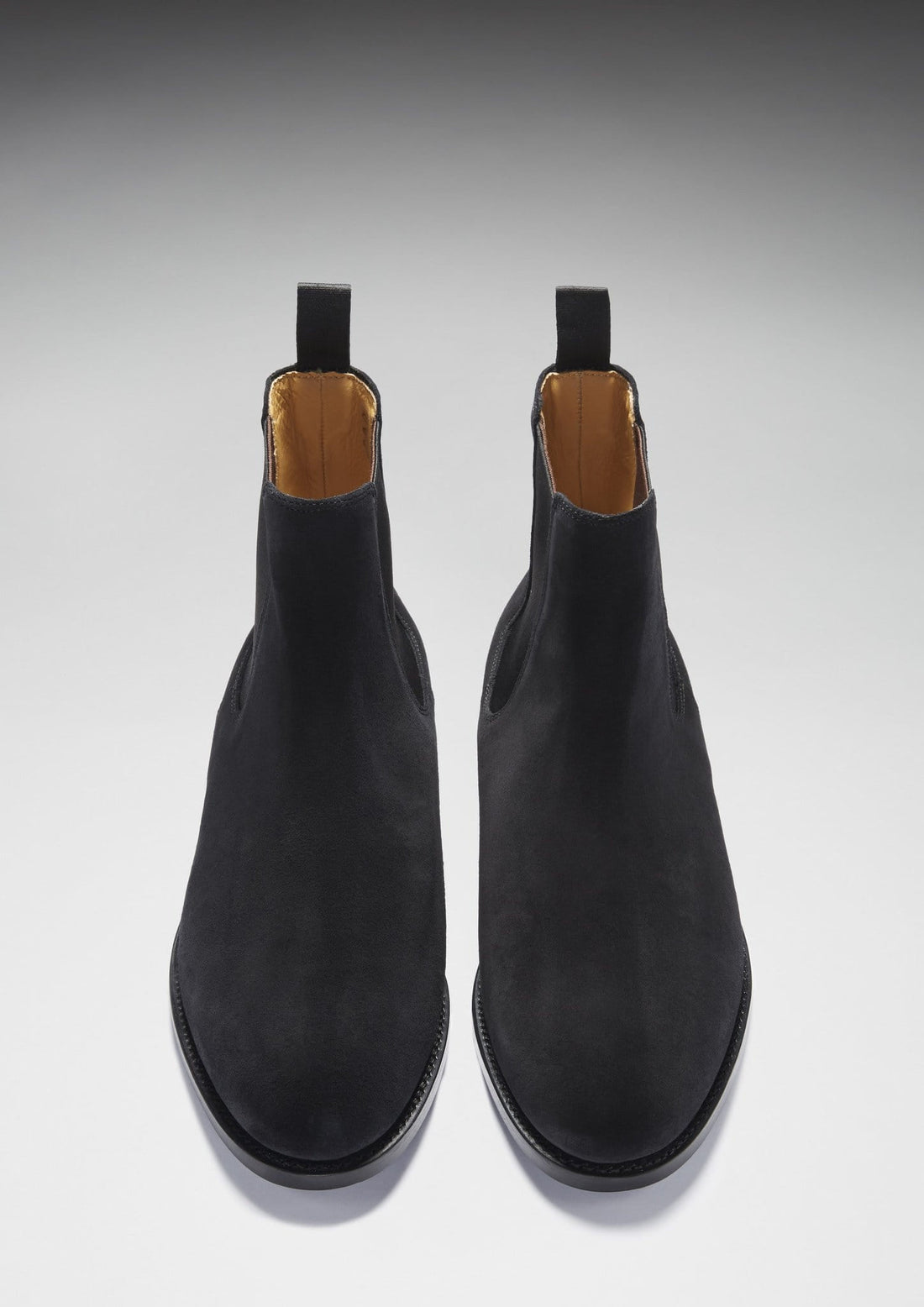 Pair of black suede Chelsea boots viewed from above, showing rounded toes and tan lining