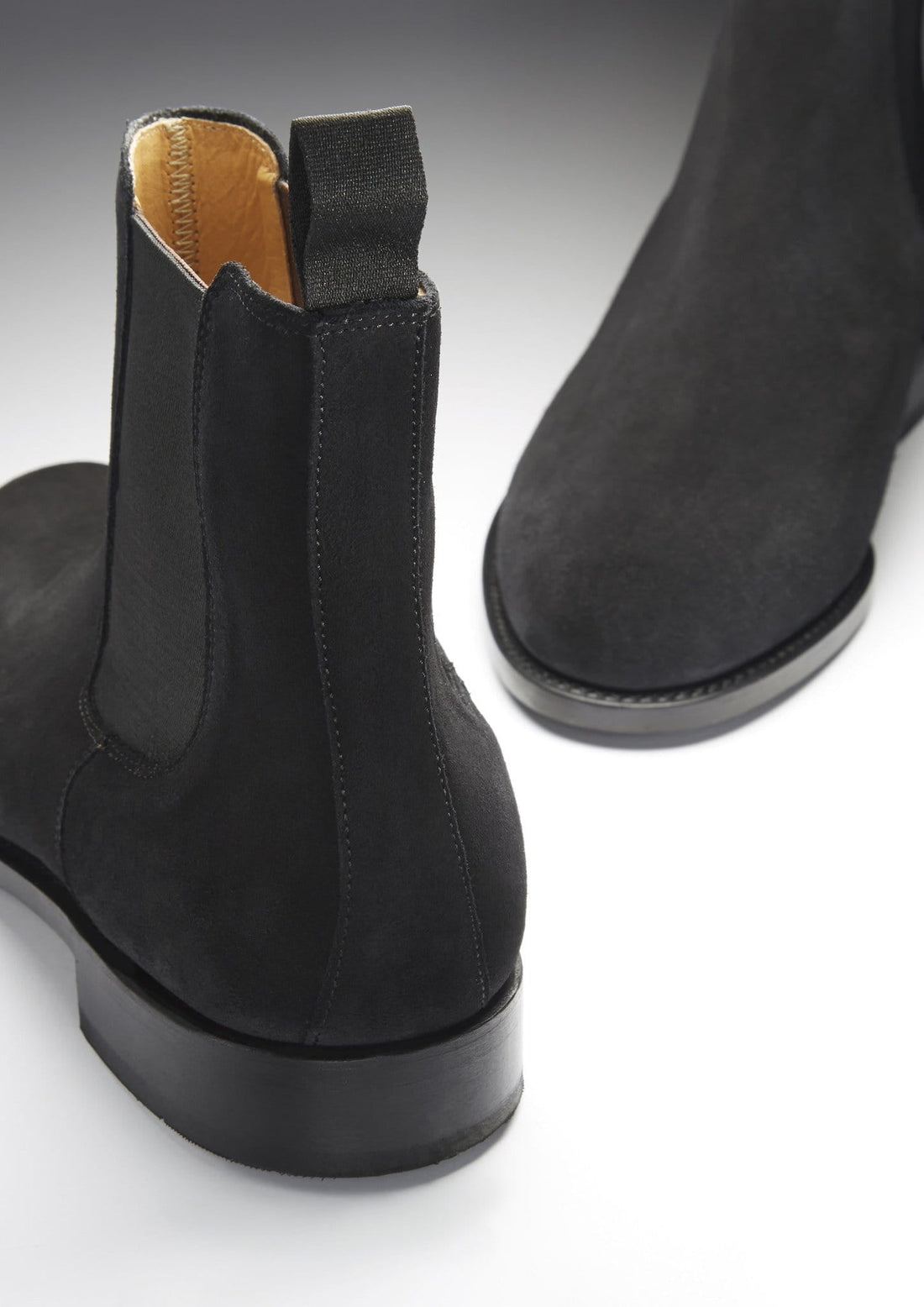 Black suede Chelsea boot showing the elastic side panel, heel, and pull tab