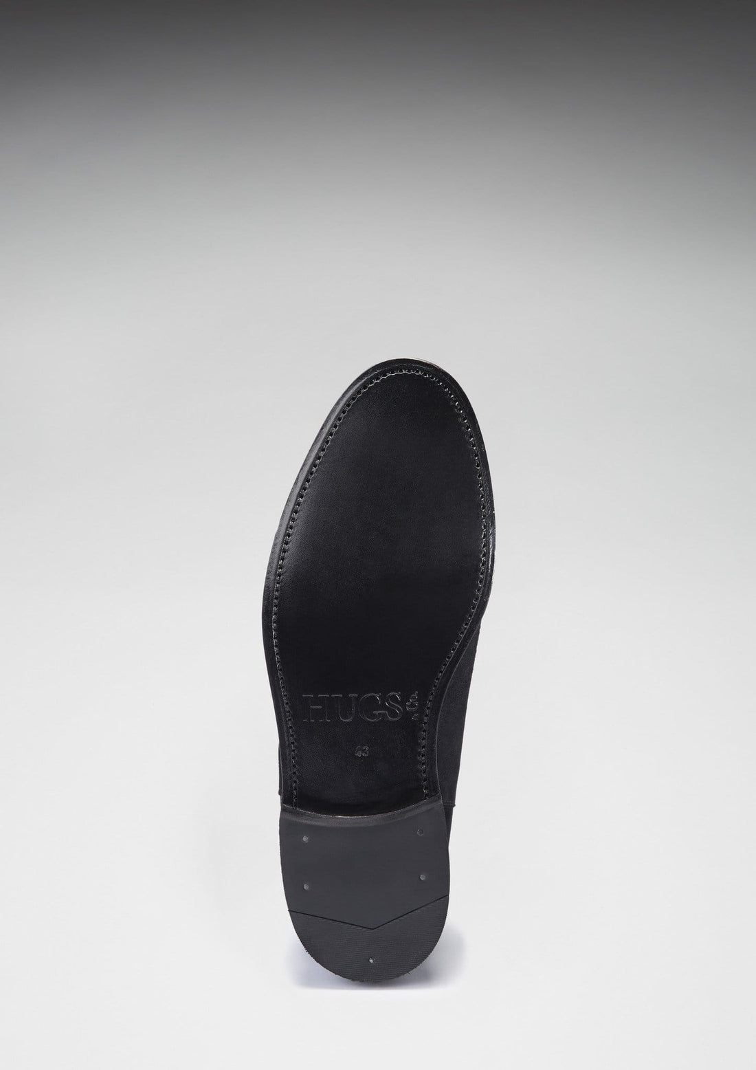 Underside of a black Chelsea boot with a leather sole and low heel