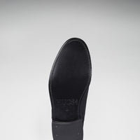 Underside of a black Chelsea boot with a leather sole and low heel
