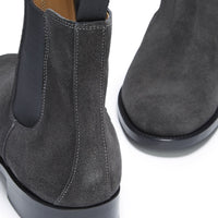Close-up of a gray suede Chelsea boot's elastic panel, stitching, and heel