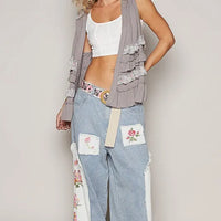 Grey sleeveless open-front cardigan with ruffled tiers and floral trim