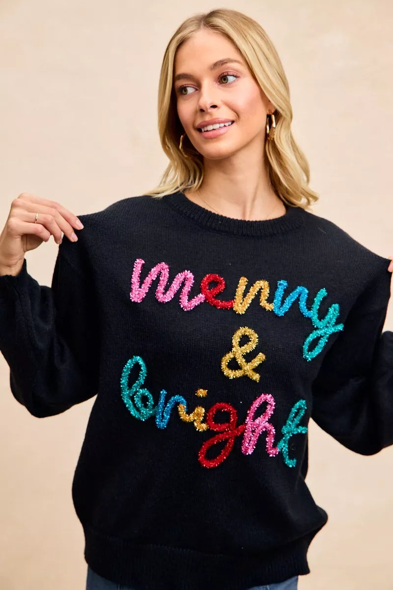 Black crewneck sweater featuring multicolor tinsel "Merry & bright" lettering.