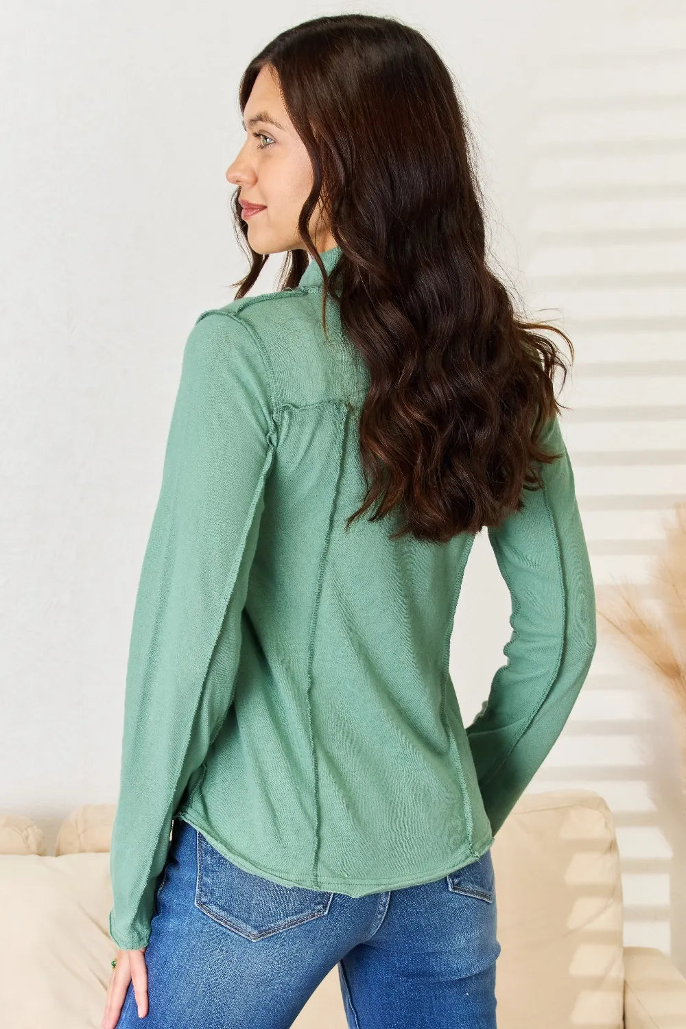Emerald green long sleeve knit top with mock neck and side exposed seam