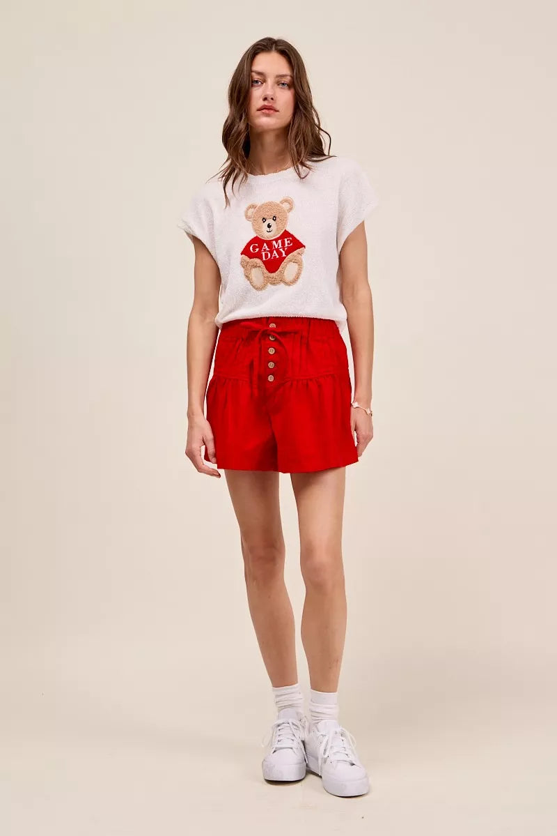 Red denim shorts with pintucked front, button closure, and elastic waistband.