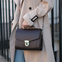 Dark leather crossbody satchel with flap front and chain shoulder strap