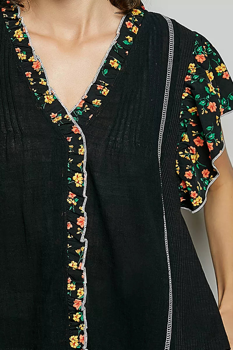 Close-up of black V-neck blouse with floral trim and pintuck front seam