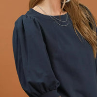 Close-up of navy round-neck sweatshirt with gathered puff sleeve detail