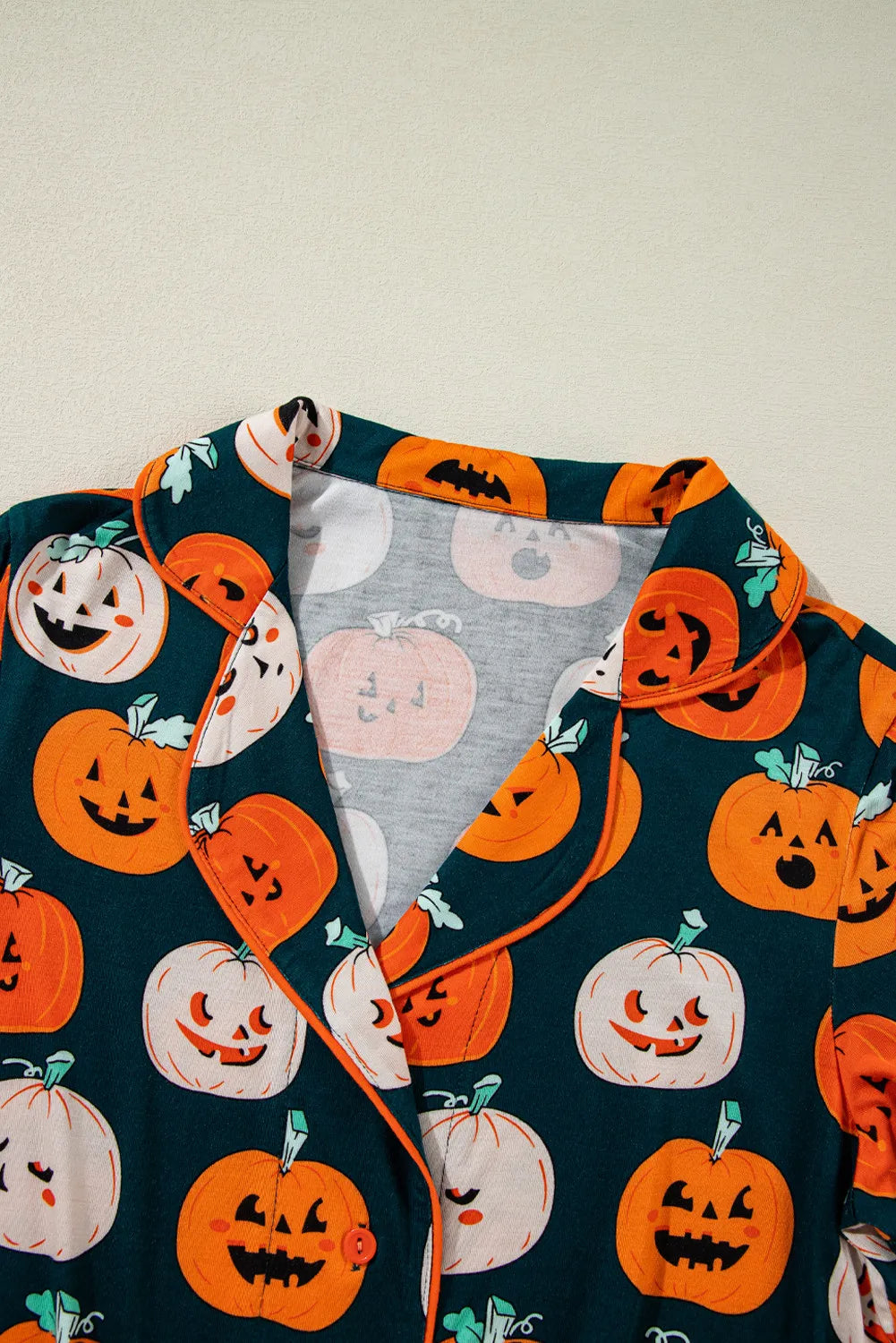 Close-up of pumpkin-printed short-sleeve collar and fabric in dark green and orange