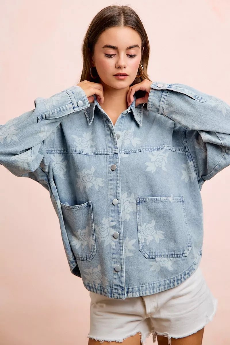 Light blue denim jacket close-up with white floral print, button front and chest pockets