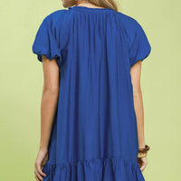 Back view of blue shift mini dress with short puff sleeves and ruffled hem.