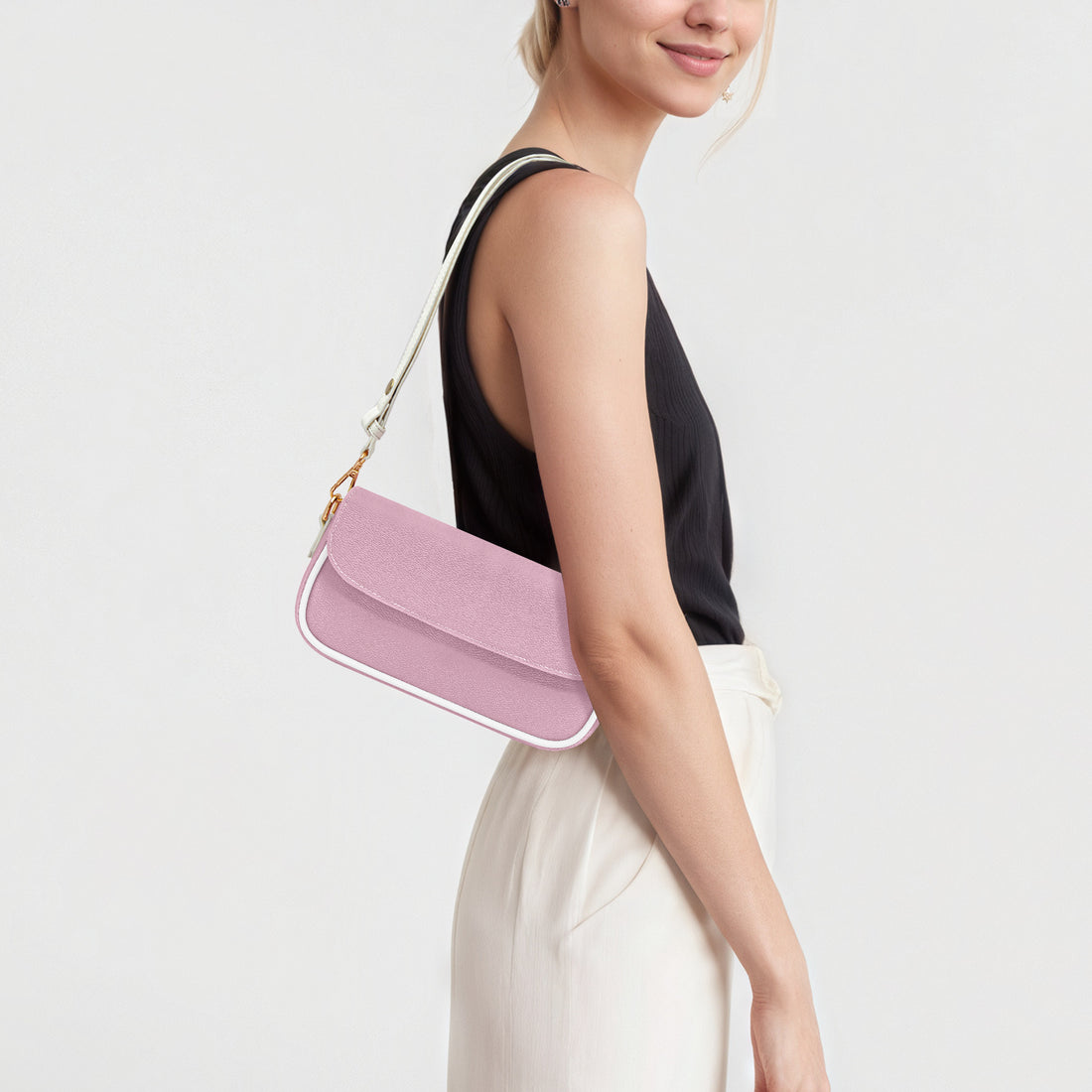 Pastel pink mini crossbody bag worn over shoulder with front flap and chain strap