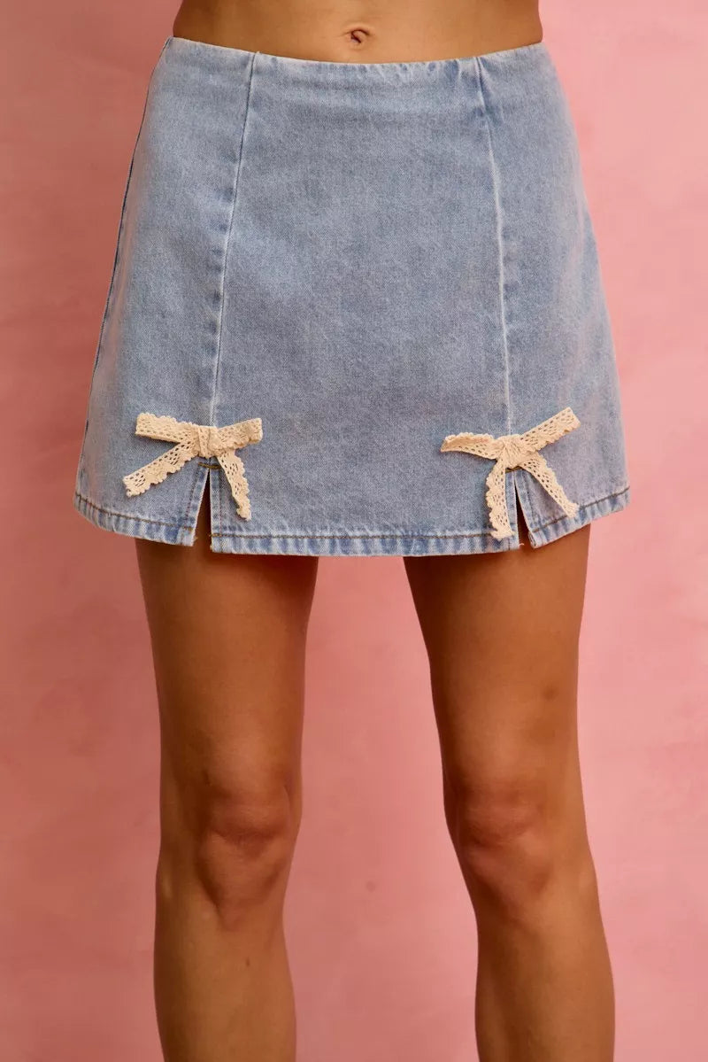 Light blue denim mini skirt featuring lace ribbon bow details along the hem.