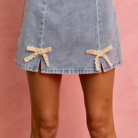 Light blue denim mini skirt featuring lace ribbon bow details along the hem.