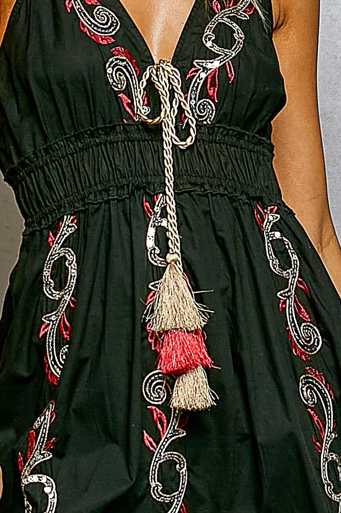 Black bodice with ornate embroidery and long tassel tie, close-up