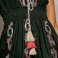 Black bodice with ornate embroidery and long tassel tie, close-up