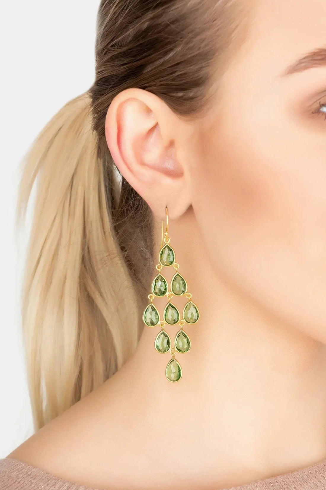 Gold peridot chandelier drop earrings with teardrop green stones, worn on ear