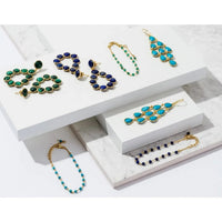 Turquoise drop earrings on a gold-tone jewelry display tray
