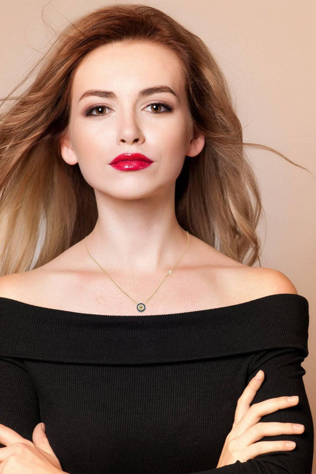 Gold evil eye necklace worn with off-shoulder top, small blue eye pendant