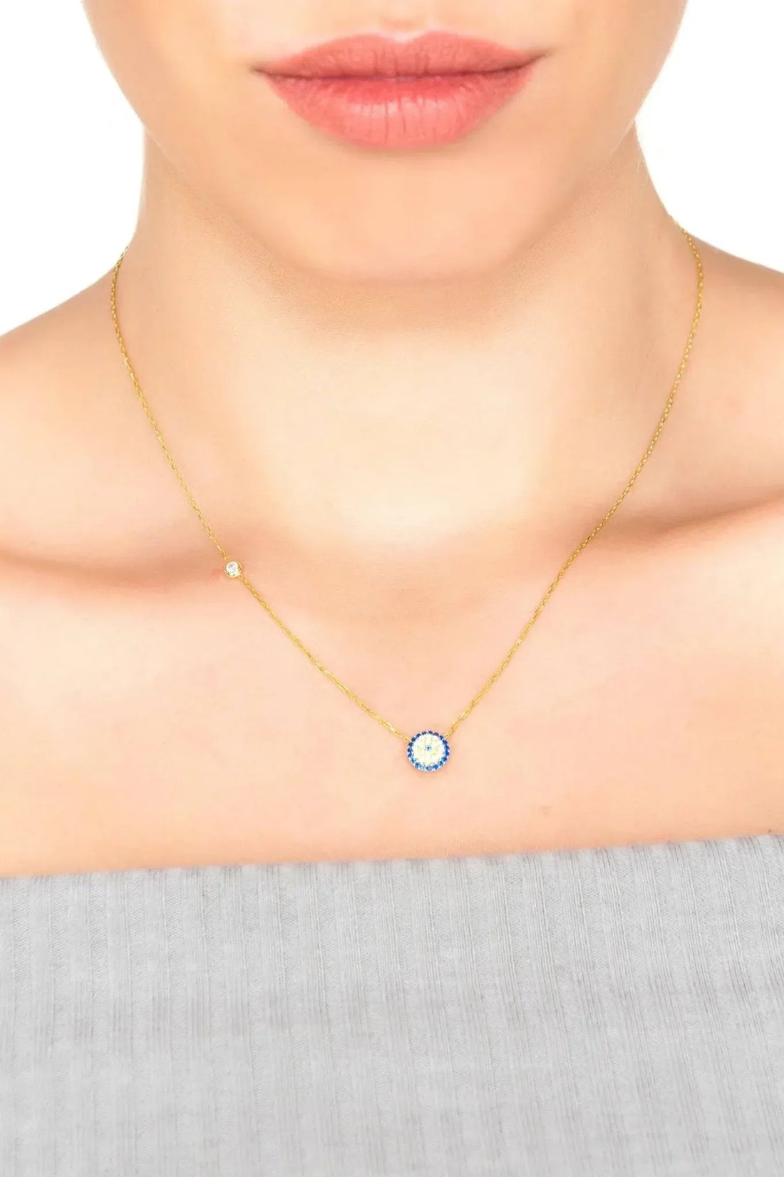 Gold evil eye necklace with small round blue eye charm on fine chain