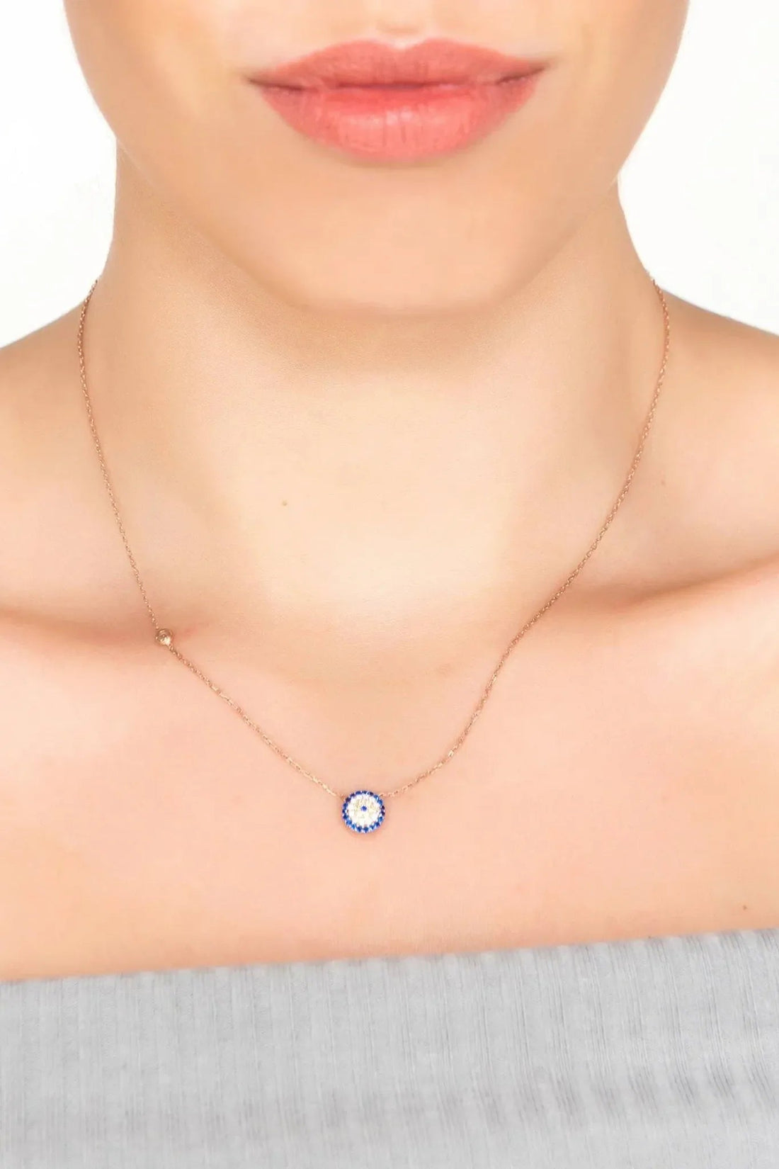 Rose gold evil eye necklace with small blue eye pendant on neckline