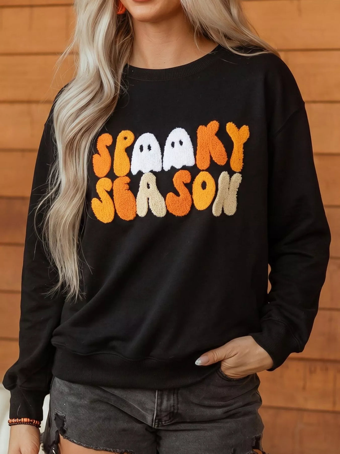 Black long-sleeve crewneck sweatshirt with embroidered spooky seasonal text front