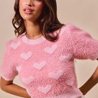 Pink cropped heart-print sweater with crew neckline and short sleeves, ribbed hem