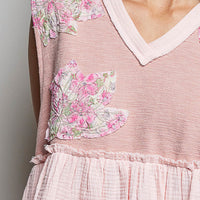 Powder pink sleeveless top close-up with V-neck trim, floral patch and raw-edge ruffle