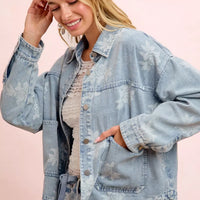Light blue washed denim jacket with white floral print and front pockets, side view