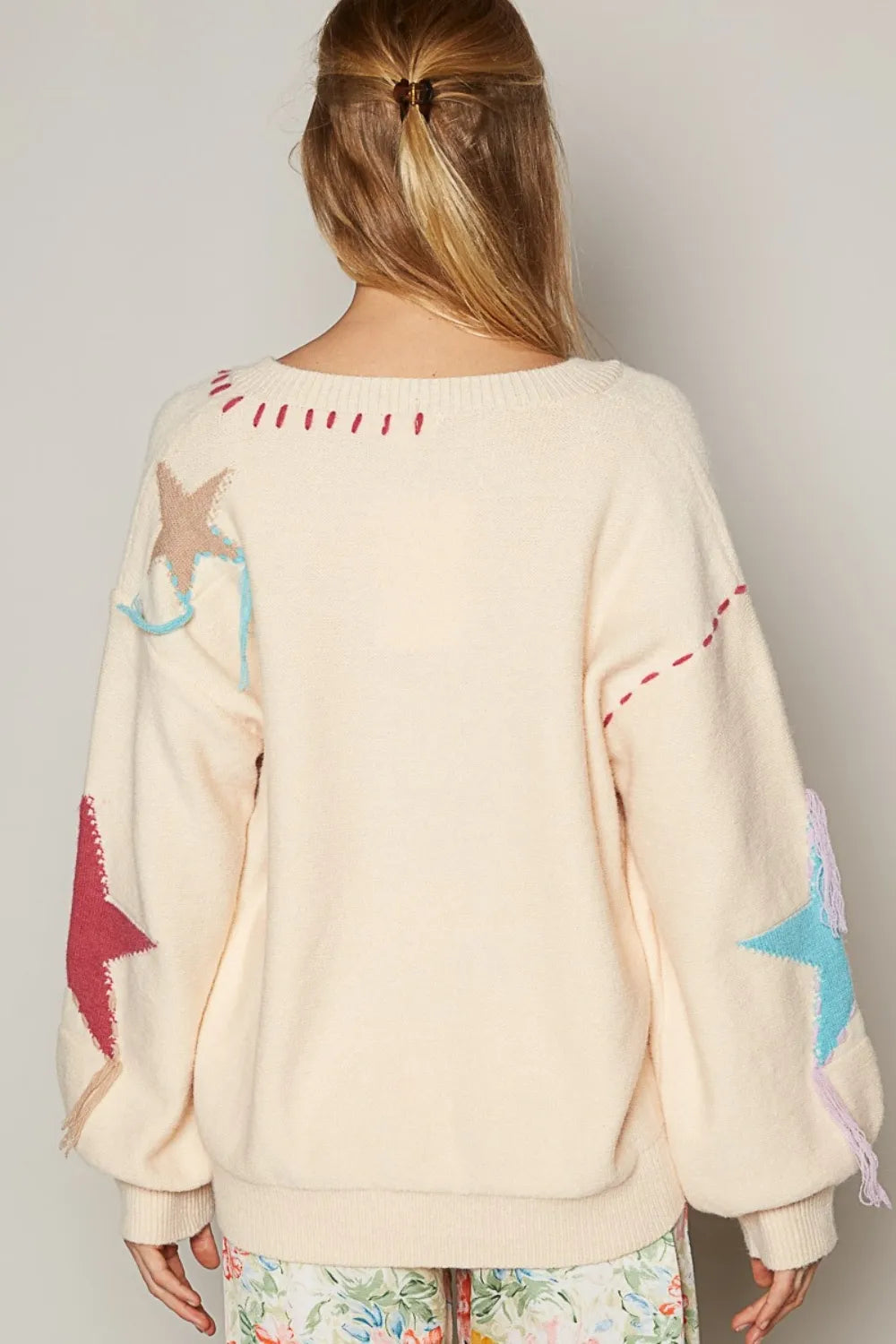Back view pale beige V-neck long-sleeve sweater with star prints and trim