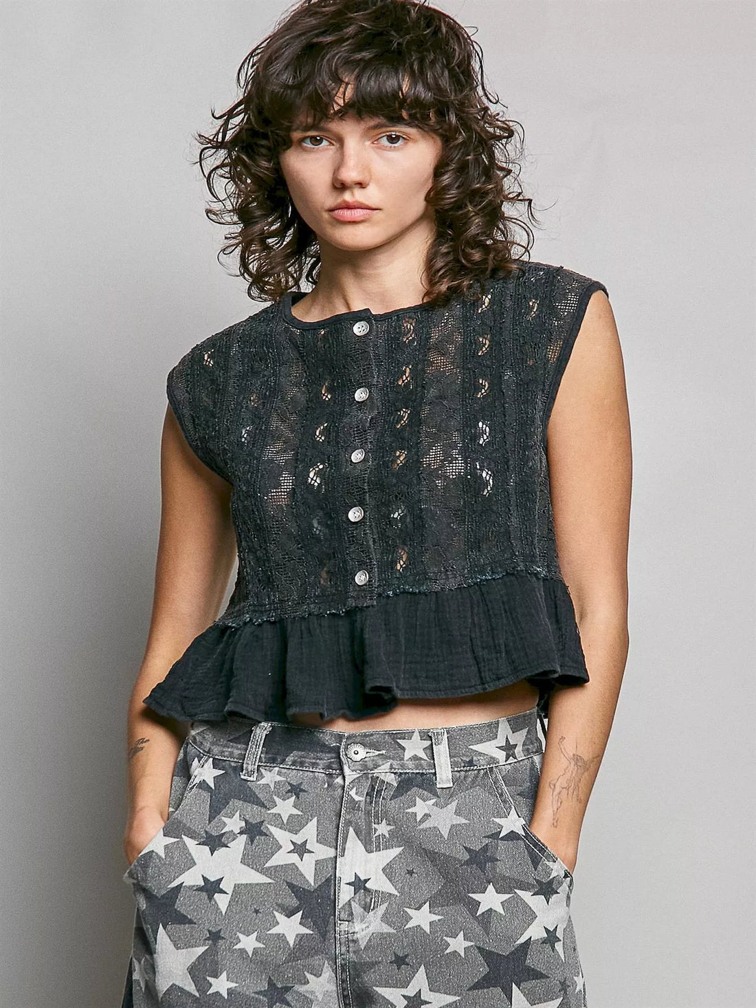 Black lace sleeveless top with round neck, button front, and ruffled peplum hem