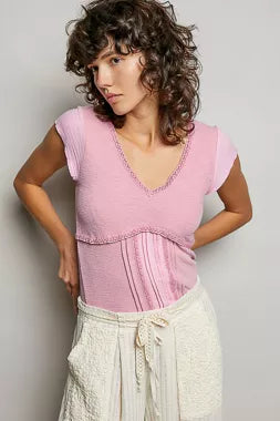 Soft pink textured knit V-neck top with lace trim and short sleeves, angled view