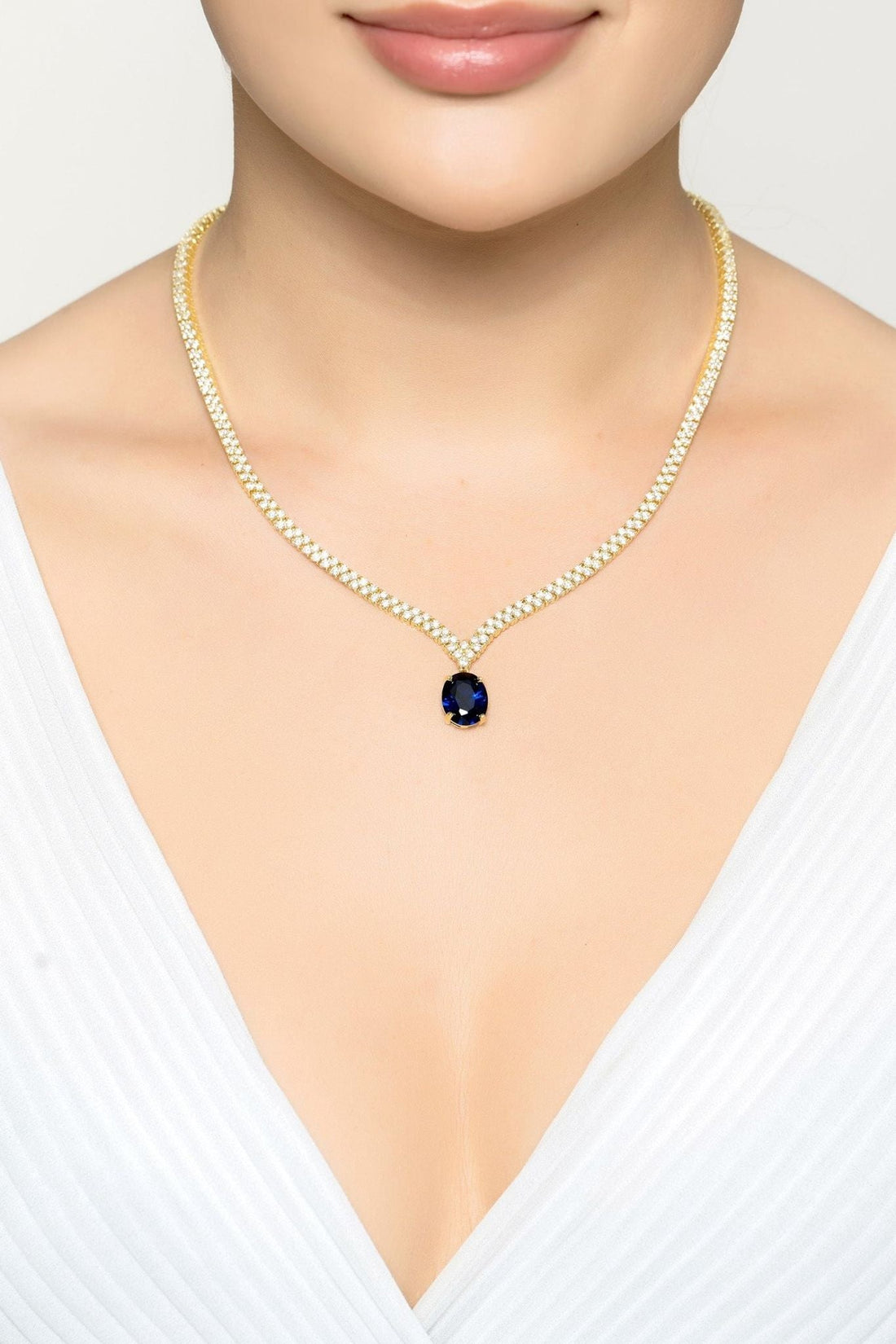 Gold tennis necklace with oval sapphire pendant