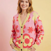 Woman wearing a pink cardigan with red floral patterns on a gradient background