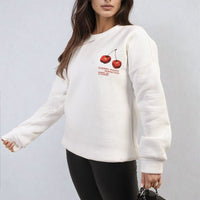 White oversized knitted jumper with crew neck and small cherry graphic on front