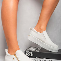 White slip-on trainers with side zipper detail and gold-tone accents on low profile sole