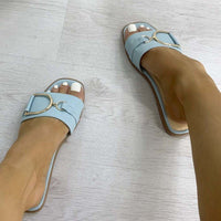 Blue open-toe slide sandals with wide strap and gold tone ring detail
