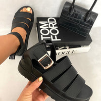 Black slide sandals with buckle strap and thick platform sole