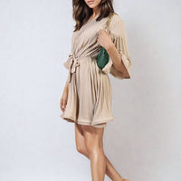 Beige pleated mini dress with tie waist and wide sleeves, pleated A-line fit.