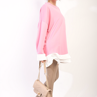 Pink oversized long-sleeve top with white ruffle hem, side view