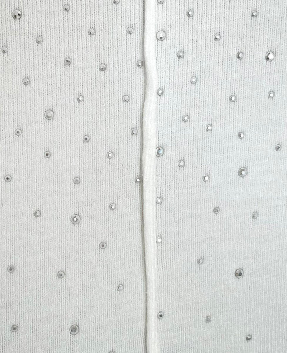 White knitted fabric close-up with rhinestone button-like specks and center seam