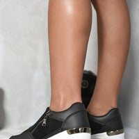 Black platform sneakers with side zip, gold accent trim, and white sole