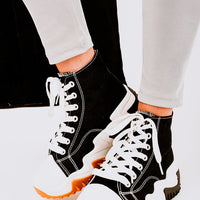 Black high-top platform trainers with white laces, white panels, and orange sole