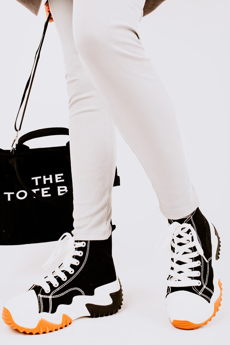 Black and white high-top platform trainers with orange tread soles