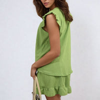 Green sleeveless ruffle-trim top and matching tiered shorts set, side view.