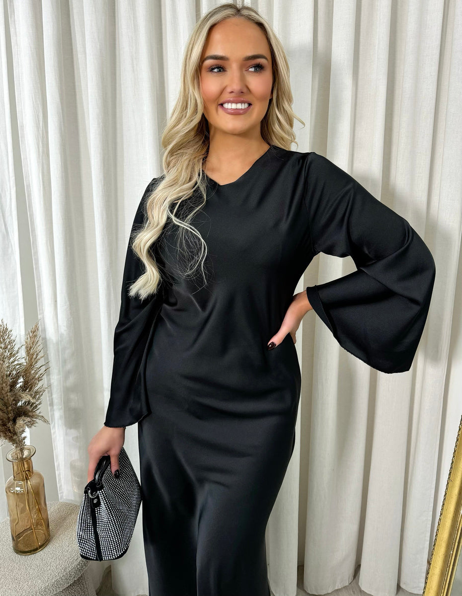Black maxi dress with round neckline and long flared sleeves, arm raised